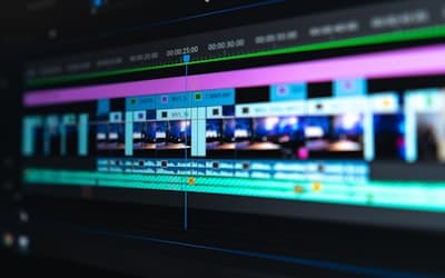 A video editing timeline with blue and purple clips on a dark screen