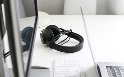 Black corded headphones on white wooden table