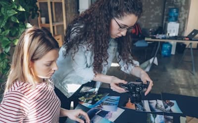 Two women examine photos at a table