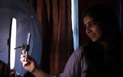 A woman holding a cell phone in front of a light