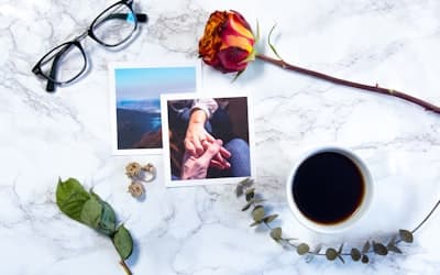 Flat-lay photography of two photos, eyeglasses, and rose