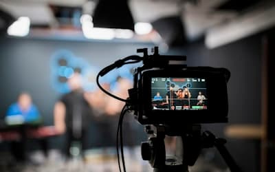 A professional video camera recording a musical group performing in a studio