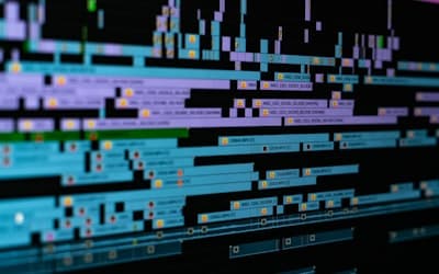 A digital video editing timeline with blue and purple clips on a black background