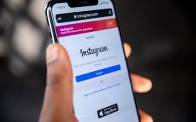 A hand holding a smartphone displaying the Instagram login page on a screen