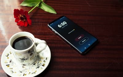 Smartphone near cup of coffee on table