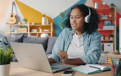 Young woman wearing headphones works on a laptop