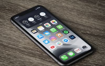 A smartphone with a home screen full of app icons on a wooden surface